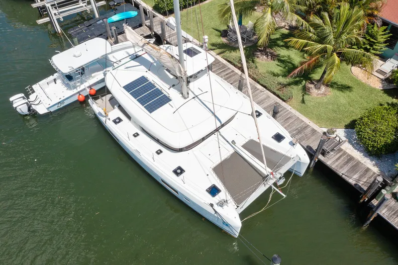 Curvy Mermaid Yacht Photos Pics Aerial view of a 2017 Lagoon 42 catamaran docked by a lush, tropical shoreline.