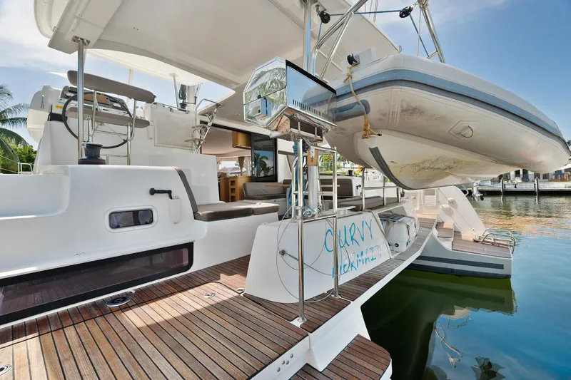 Curvy Mermaid Yacht Photos Pics 2017 Lagoon 42 catamaran with dinghy, docked at marina, featuring spacious deck and seating area.