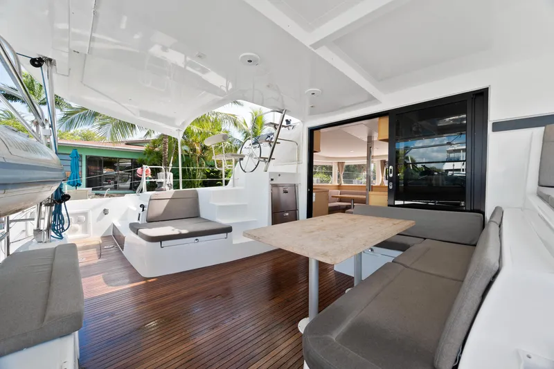 Curvy Mermaid Yacht Photos Pics 2017 Lagoon 42 catamaran interior with seating, table, and helm, featuring modern design and wood flooring.