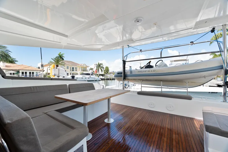 Curvy Mermaid Yacht Photos Pics Spacious deck of 2017 Lagoon 42 catamaran with seating and table, docked at marina.