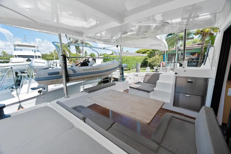 Curvy Mermaid Yacht Photos Pics Spacious deck of 2017 Lagoon 42 catamaran with seating, table, and dinghy.
