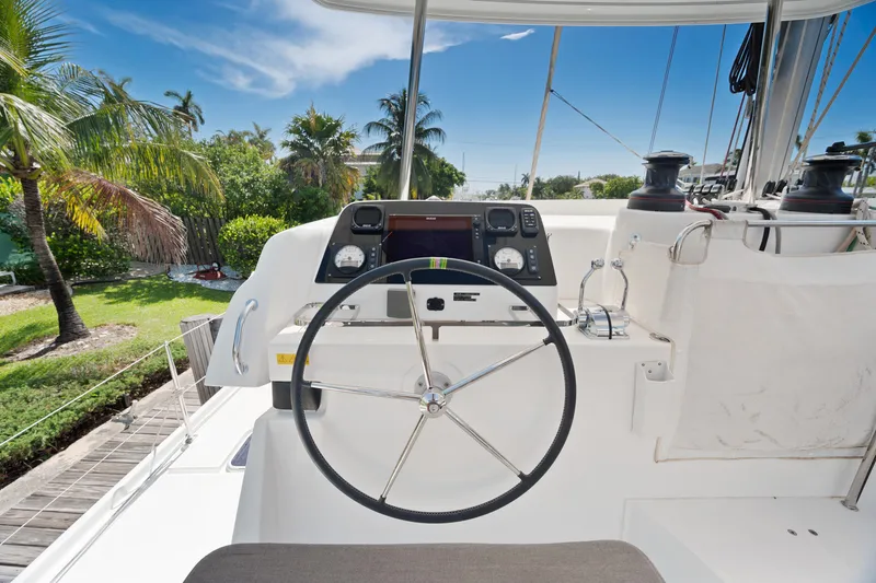 Curvy Mermaid Yacht Photos Pics Helm of 2017 Lagoon 42 catamaran with navigation instruments, surrounded by tropical greenery.