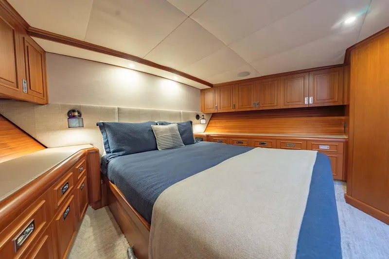 Catch Yacht Photos Pics Luxurious bedroom interior of 1984 Feadship Yacht Fish with wooden cabinetry and cozy bedding.