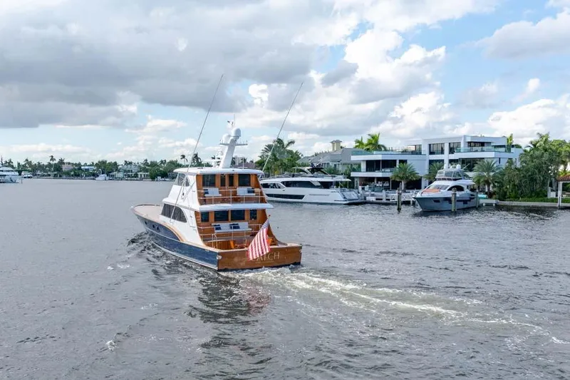 Catch Yacht Photos Pics 1984 Feadship Yacht Fish cruising on a scenic waterway near luxury waterfront homes.