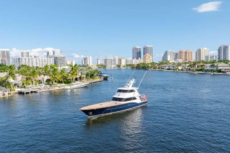 Catch Yacht Photos Pics 1984 Feadship Yacht Fish cruising on a scenic waterway with city skyline backdrop.