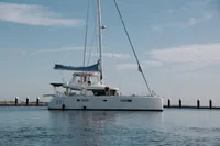 2013 Lagoon 52 F catamaran sailing on calm waters near a marina.