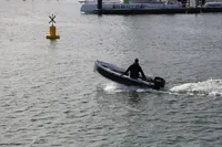 Small motorboat navigating near a buoy in a marina, with a Lagoon 52 F in the background.
