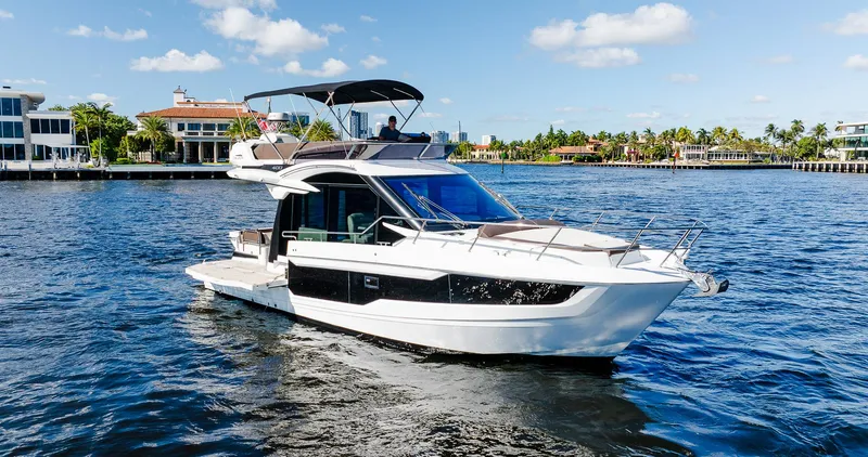 Lei Vola Yacht Photos Pics Galeon 400 Fly 2022 yacht cruising on a sunny day, near waterfront homes.