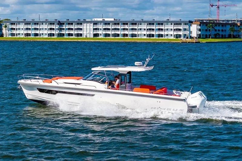  Yacht Photos Pics 2023 Nimbus Tender 11 cruising on a sunny day near waterfront buildings.