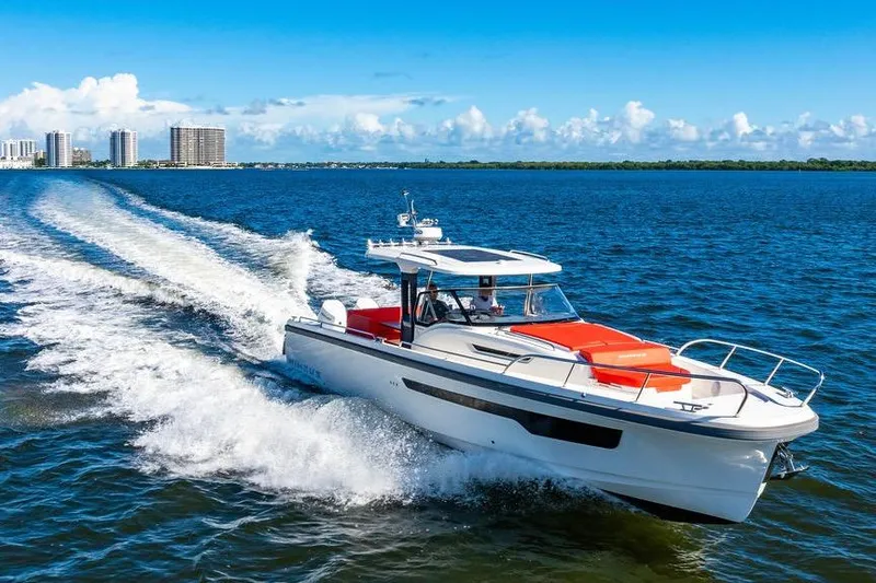  Yacht Photos Pics 2023 Nimbus Tender 11 cruising on blue ocean with city skyline in background.
