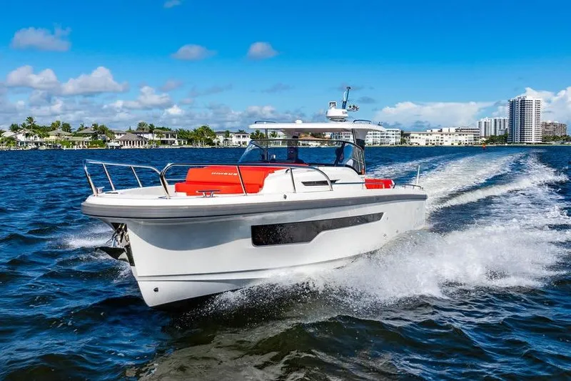  Yacht Photos Pics 2023 Nimbus Tender 11 cruising on a sunny day, creating waves in a scenic coastal setting.