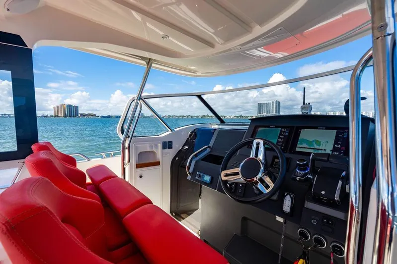  Yacht Photos Pics Interior view of 2023 Nimbus Tender 11 boat with red seats and modern dashboard.