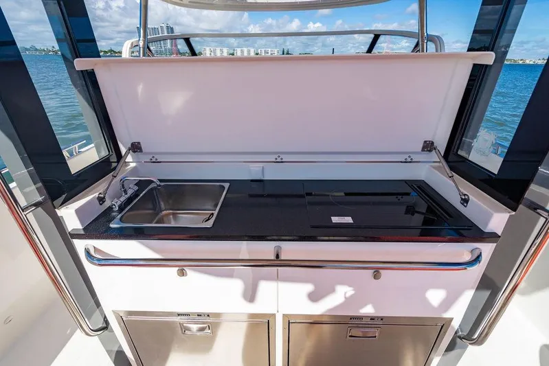  Yacht Photos Pics Outdoor kitchenette on 2023 Nimbus Tender 11 yacht with sink and stove, overlooking water.