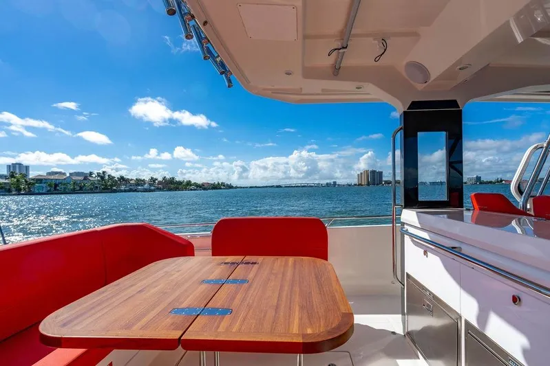  Yacht Photos Pics Luxurious 2023 Nimbus Tender 11 yacht interior with red seating and wooden table, ocean view.