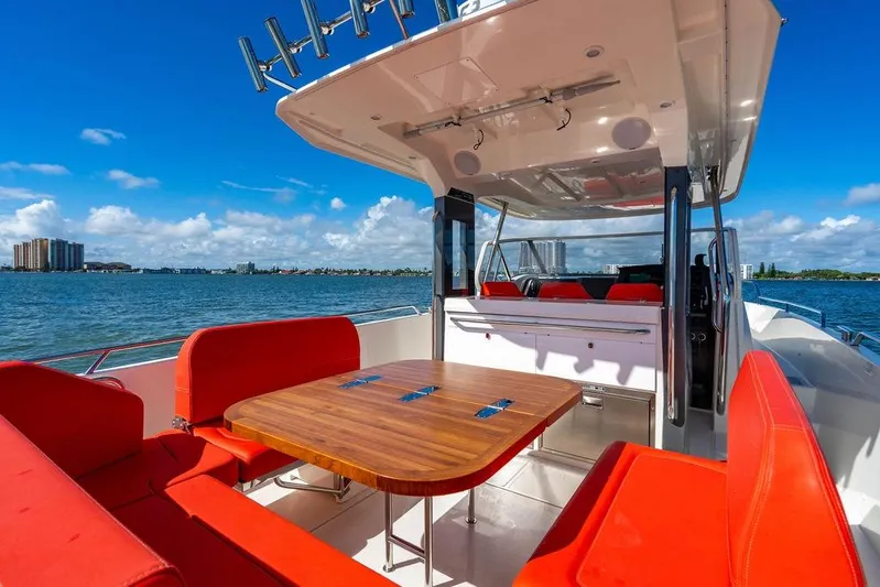  Yacht Photos Pics Luxurious 2023 Nimbus Tender 11 boat with red seating and wooden table on a sunny day.