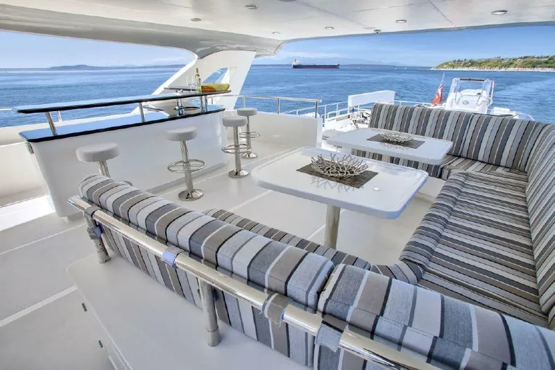  Yacht Photos Pics Luxurious Selene 92 Explorer yacht deck with striped seating, bar stools, and ocean view, 2026 model.