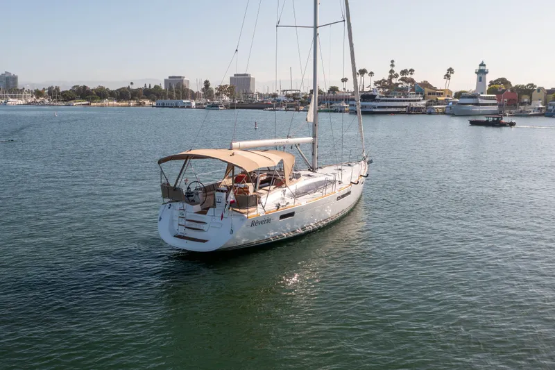 Shenanigans Yacht Photos Pics 2015 Jeanneau 53DS sailboat on calm water near a coastal cityscape.