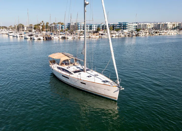 Shenanigans Yacht Photos Pics 2015 Jeanneau 53DS sailboat on calm marina waters, surrounded by yachts.