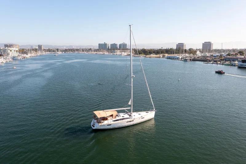 Shenanigans Yacht Photos Pics 2015 Jeanneau 53DS sailboat cruising in a calm marina with city skyline.