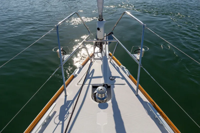 Shenanigans Yacht Photos Pics Bow of 2015 Jeanneau 53DS sailboat on calm water, sunlight reflecting.