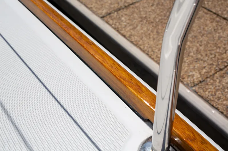 Shenanigans Yacht Photos Pics Close-up of Jeanneau 53DS 2015 yacht deck with polished wood and metal railing.