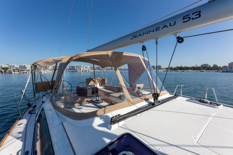 Shenanigans Yacht Photos Pics 2015 Jeanneau 53DS sailboat on calm water, featuring spacious deck and canopy.
