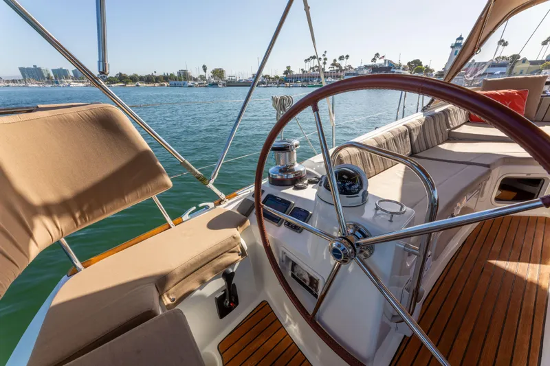 Shenanigans Yacht Photos Pics Jeanneau 53DS 2015 sailboat cockpit with wooden deck and steering wheel, docked in marina.