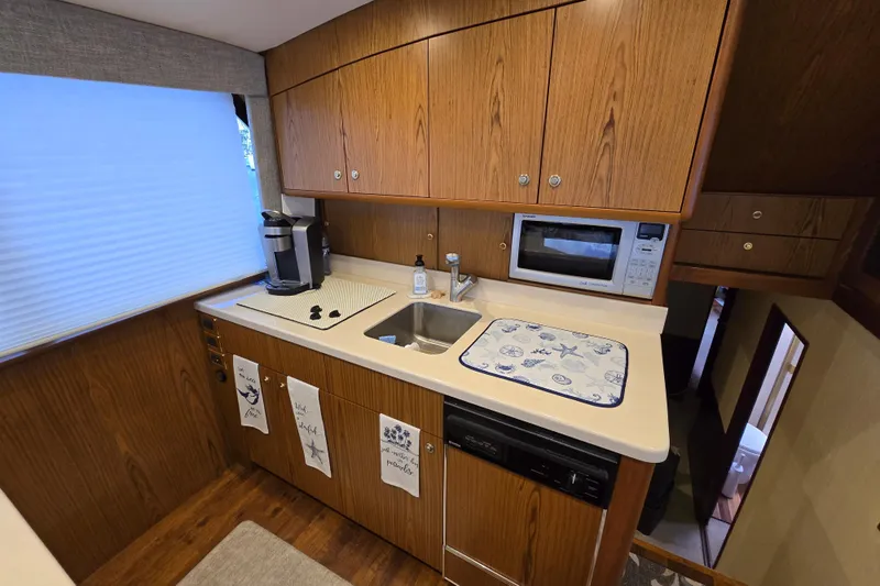  Yacht Photos Pics Galley kitchen in 1982 Ocean Yachts 55 Super Sport, featuring wood cabinets and modern appliances.
