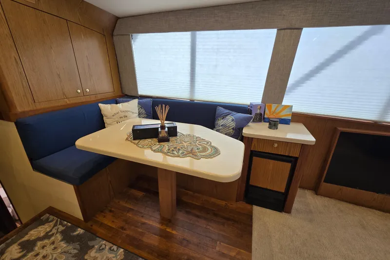  Yacht Photos Pics Cozy dining area in 1982 Ocean Yachts 55 Super Sport, featuring blue cushions and wooden cabinetry.