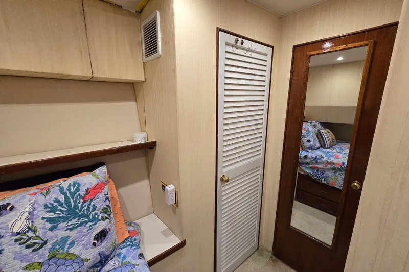  Yacht Photos Pics Cozy cabin interior of 1982 Ocean Yachts 55 Super Sport, featuring vibrant bedding and mirrored door.