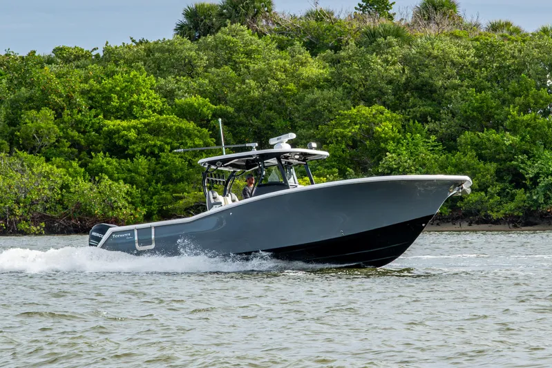 Going Propless Yacht Photos Pics 2020 Tidewater 320 CC Adventure boat cruising on water near lush greenery.