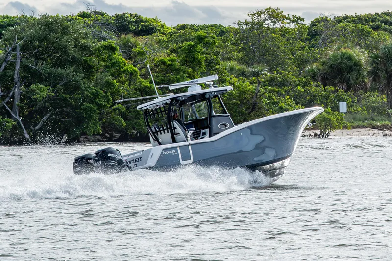 Going Propless Yacht Photos Pics 2020 Tidewater 320 CC Adventure boat cruising on water near lush green shoreline.