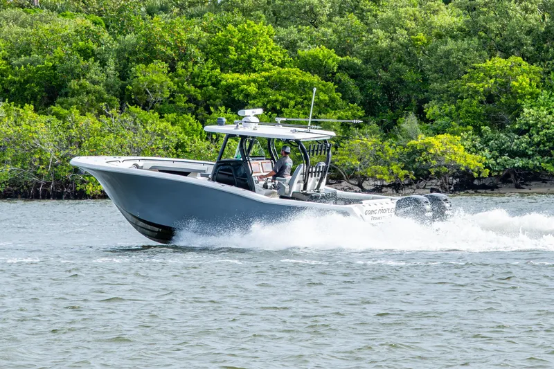 Going Propless Yacht Photos Pics 2020 Tidewater 320 CC Adventure boat cruising on water near lush green shoreline.