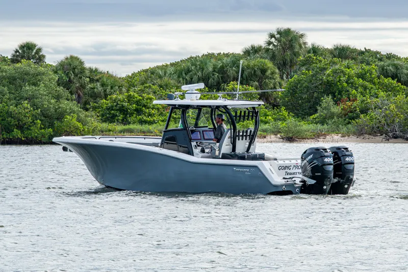 Going Propless Yacht Photos Pics 2020 Tidewater 320 CC Adventure boat on water near lush greenery.