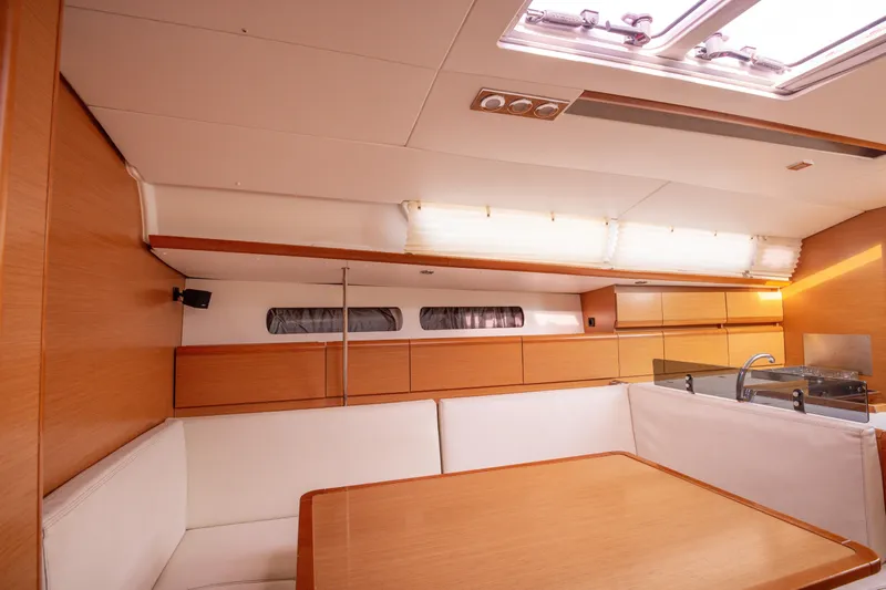  Yacht Photos Pics Interior of 2013 Jeanneau Sun Odyssey 439 yacht, featuring modern wood finish and seating area.