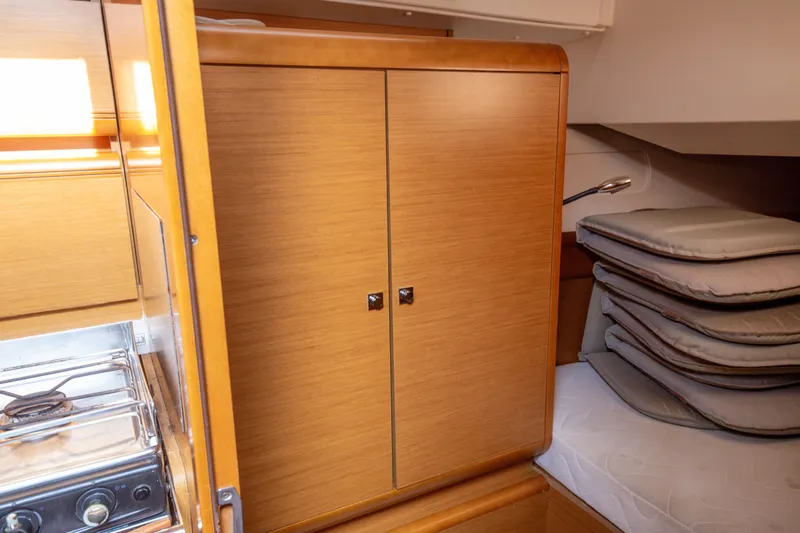  Yacht Photos Pics Interior of 2013 Jeanneau Sun Odyssey 439 yacht with wooden cabinetry and compact stove.