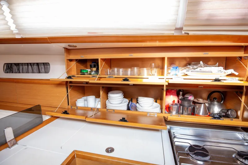  Yacht Photos Pics Interior of 2013 Jeanneau Sun Odyssey 439 yacht kitchen with open cabinets and kitchenware.