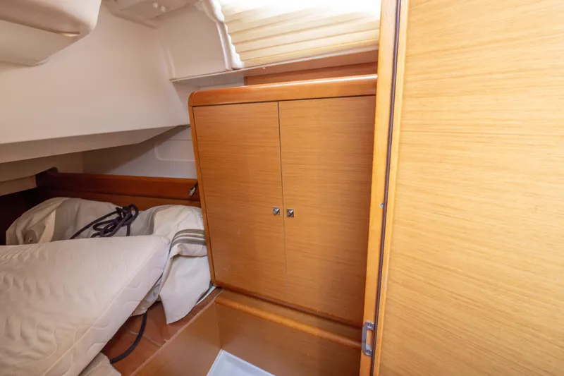  Yacht Photos Pics 2013 Jeanneau Sun Odyssey 439 cabin interior with wooden cabinetry and bedding.