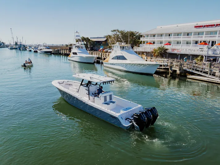  Yacht Photos Pics 2025 Invincible 36 Open Fisherman boat cruising near a marina with other vessels.