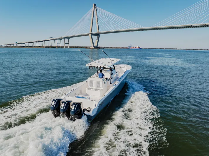  Yacht Photos Pics 2025 Invincible 36 Open Fisherman boat cruising under a large bridge.
