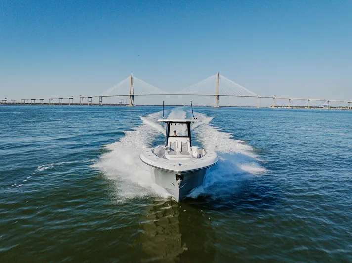  Yacht Photos Pics 2025 Invincible 36 Open Fisherman boat cruising under a bridge on a sunny day.