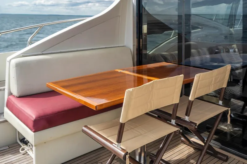  Yacht Photos Pics Outdoor seating area on 2007 Azimut 68S yacht with wooden table and cushioned chairs.