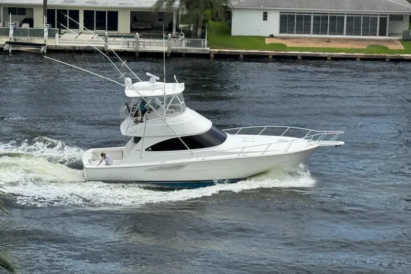  Yacht Photos Pics 2019 Viking 44 Convertible yacht cruising on a river near waterfront homes.