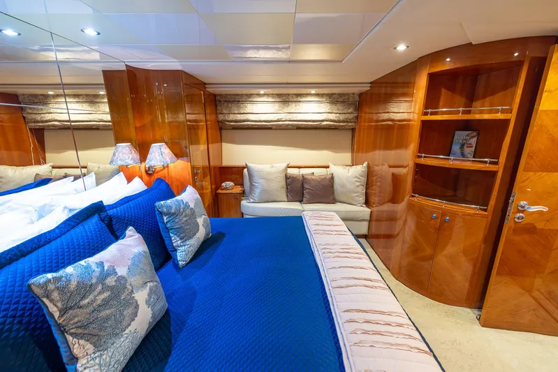  Yacht Photos Pics Luxurious bedroom in a 1999 Azimut 100 Jumbo yacht with blue bedding and wooden cabinetry.