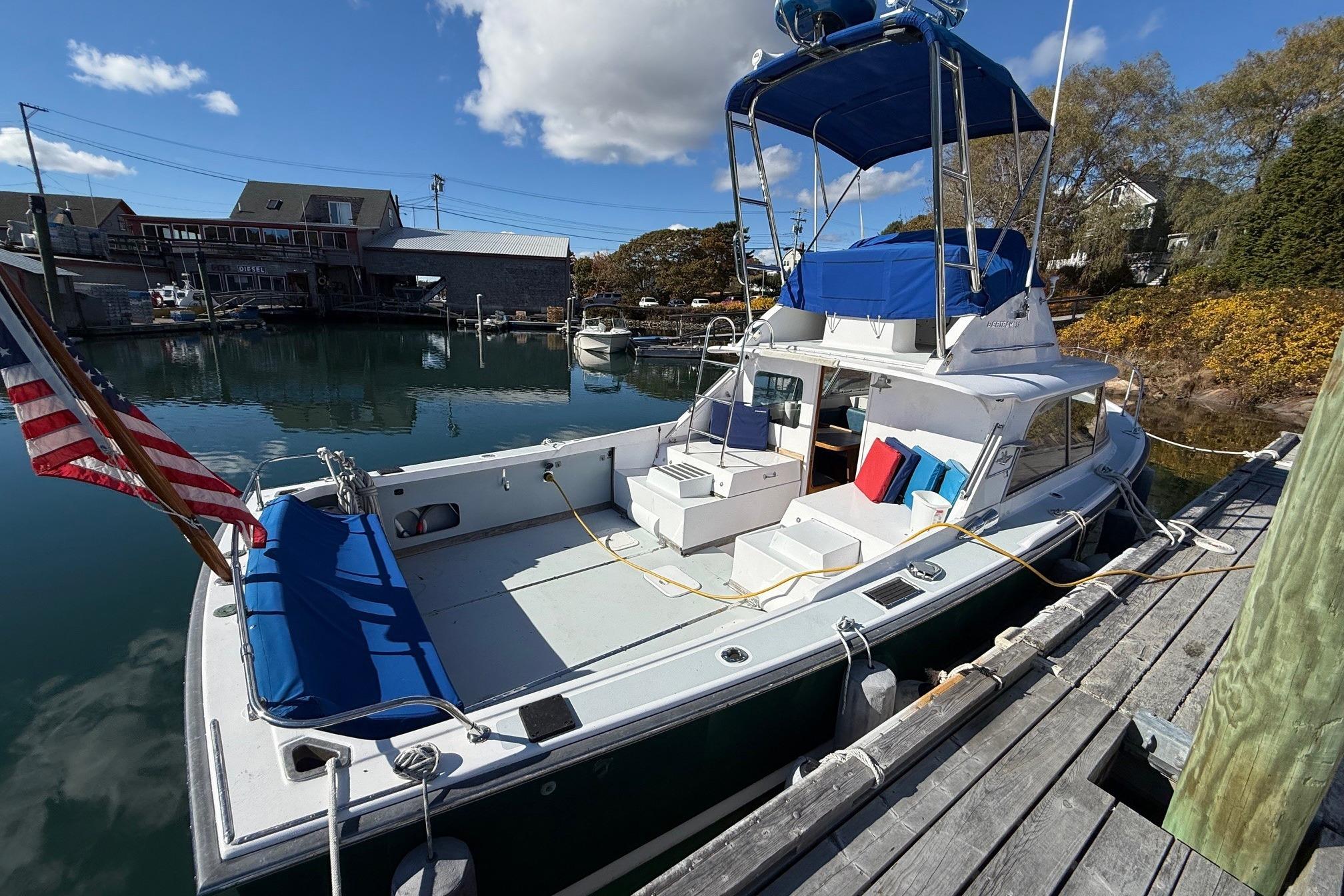 1963 Bertram 31 Flybridge Cruiser docked, featuring blue seating and American flag.