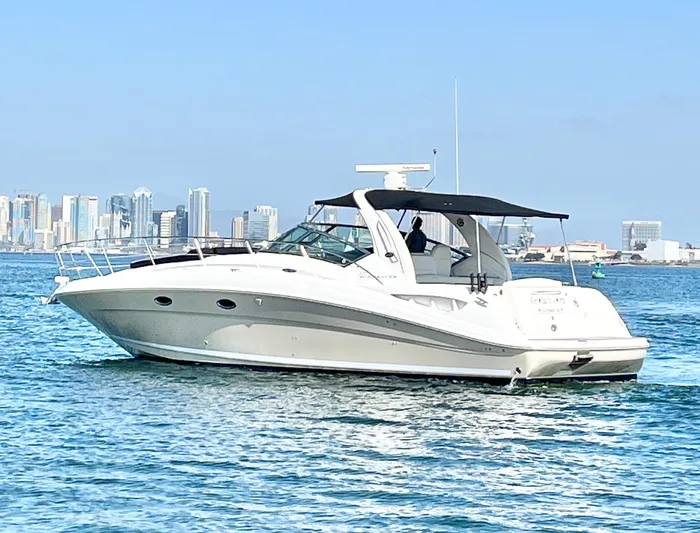  Yacht Photos Pics 2005 Sea Ray 390 Sundancer yacht cruising on blue water with city skyline backdrop.