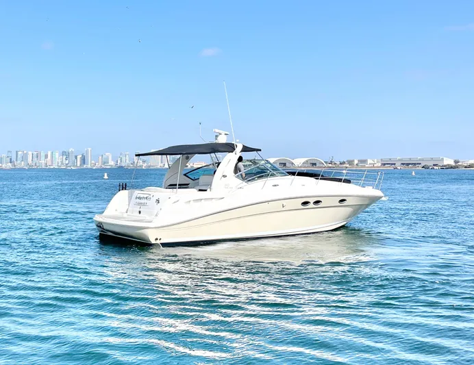  Yacht Photos Pics 2005 Sea Ray 390 Sundancer yacht cruising on blue water with city skyline in background.