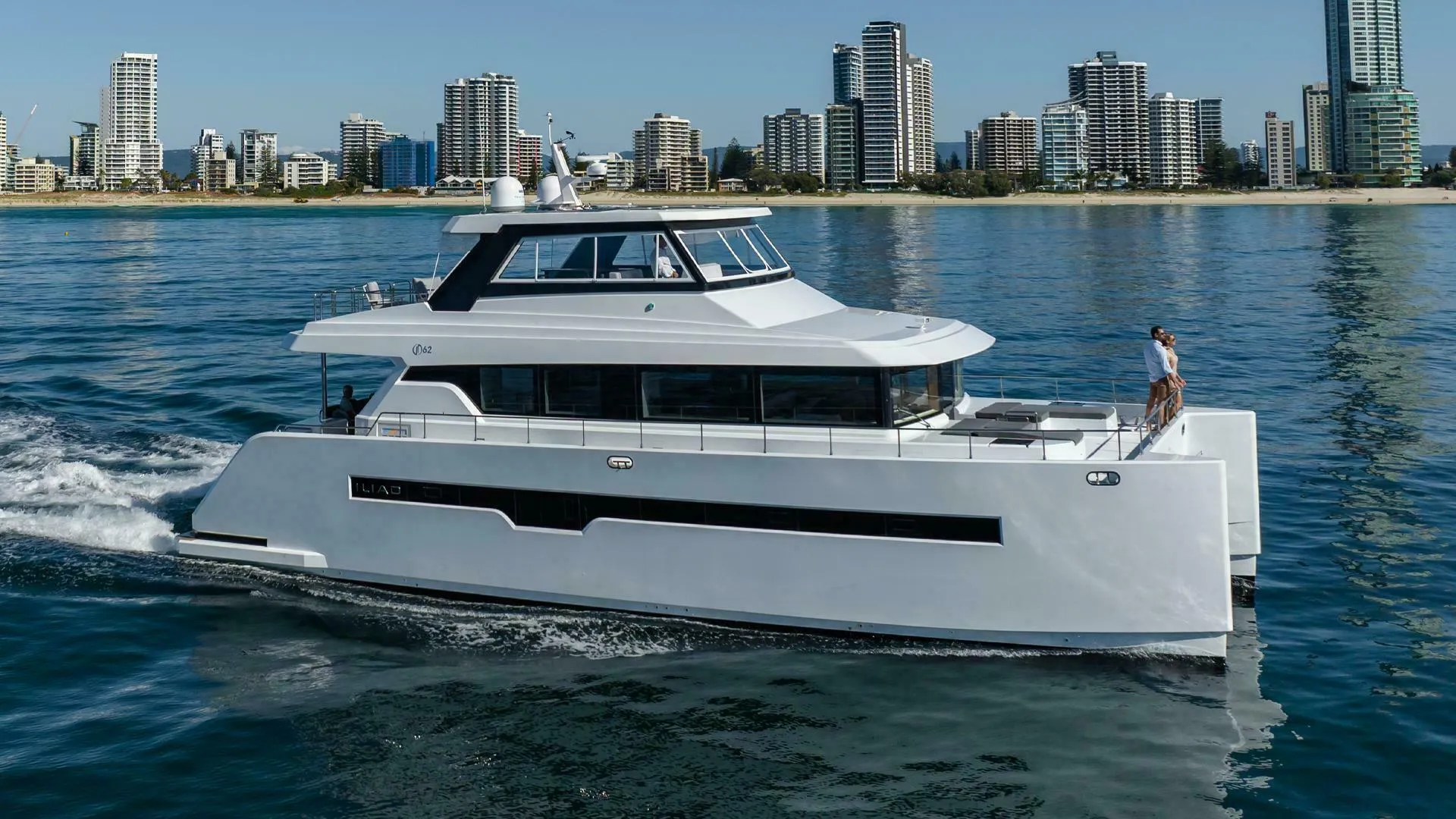Luxury ILIAD 62 yacht cruising near city skyline, 2026 model.