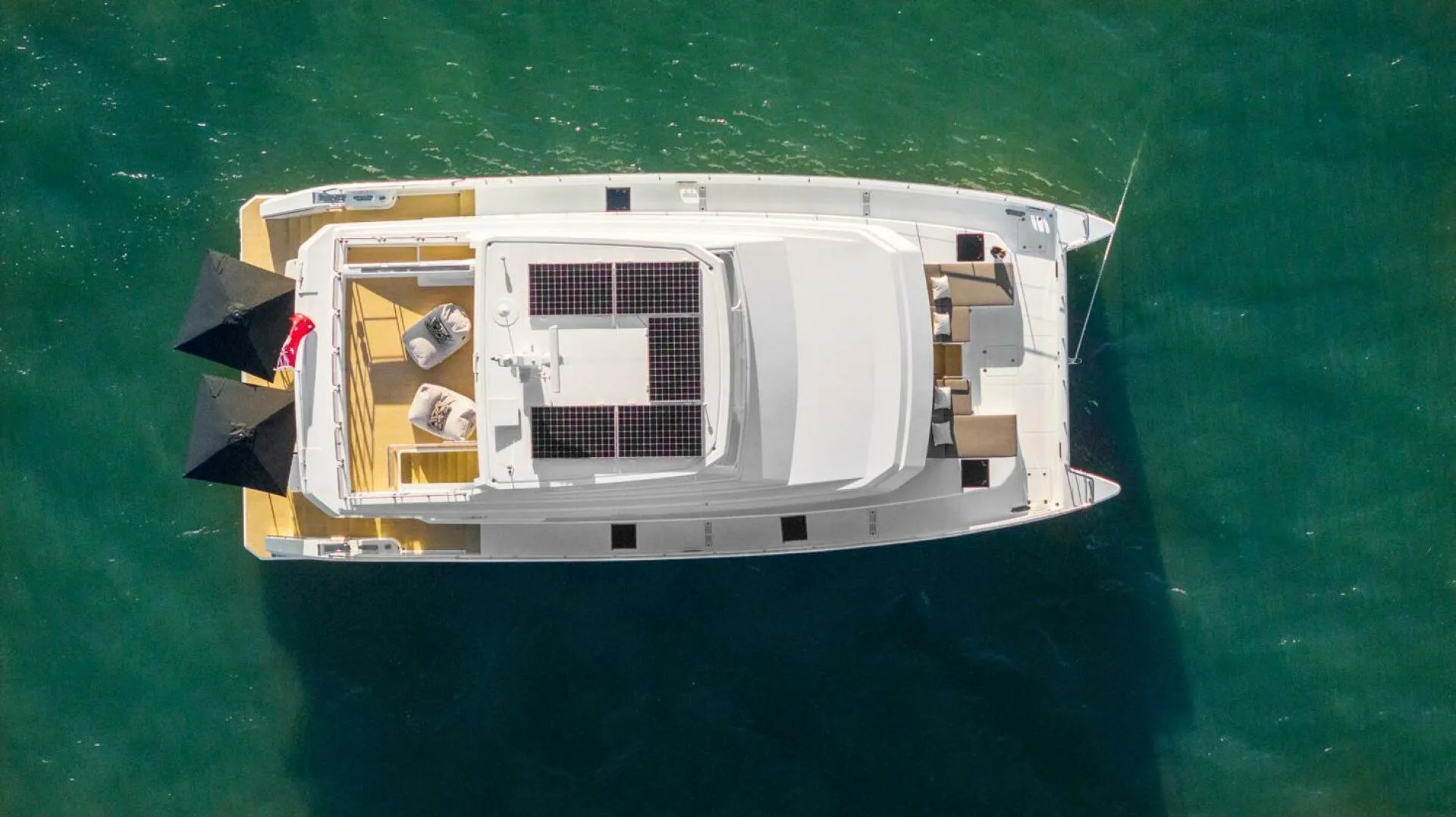 Aerial view of 2026 ILIAD 62 yacht with solar panels on turquoise water.