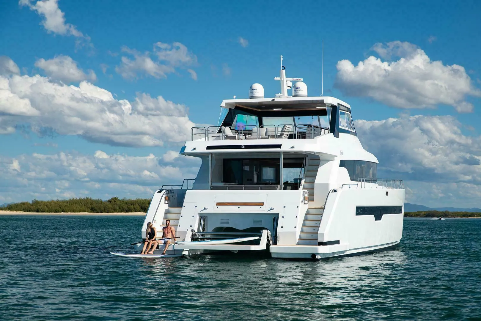 Luxurious 2026 ILIAD 62 yacht on serene water under a clear blue sky.